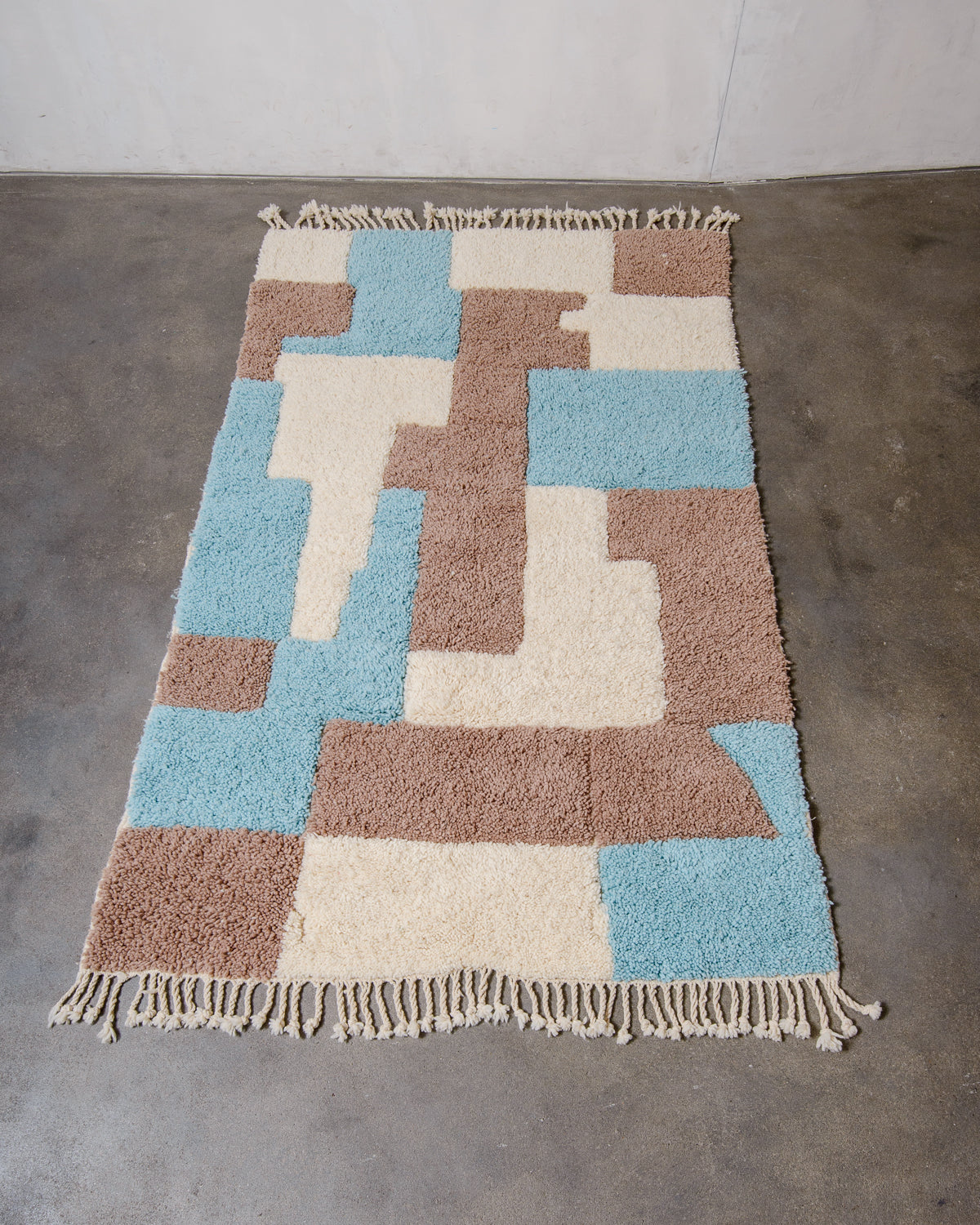 Berberlin Beniourain rug in fluffy wool, laying flat on concrete studio floor.